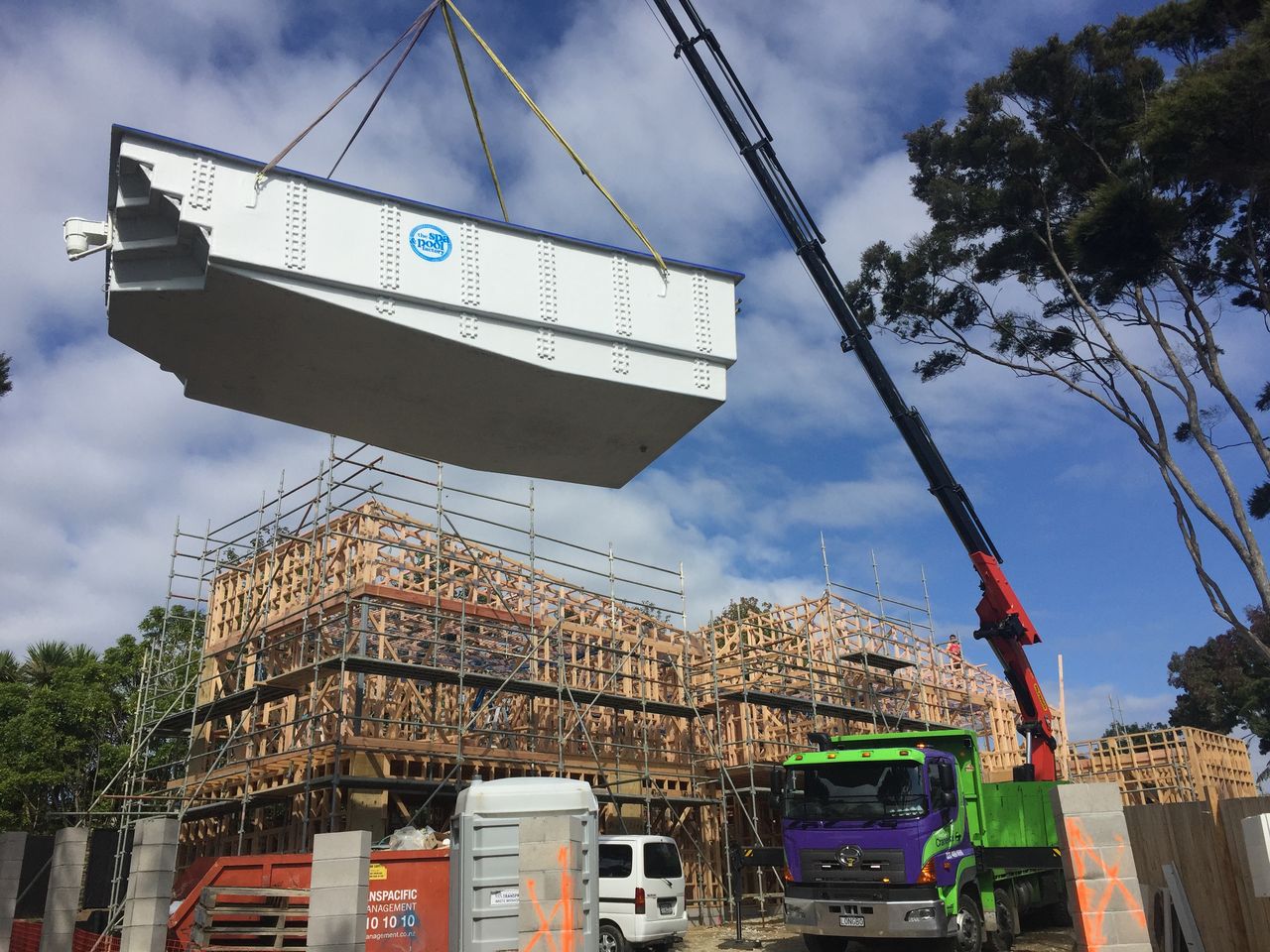 A large precast panel lifted over a scaffolded building under construction