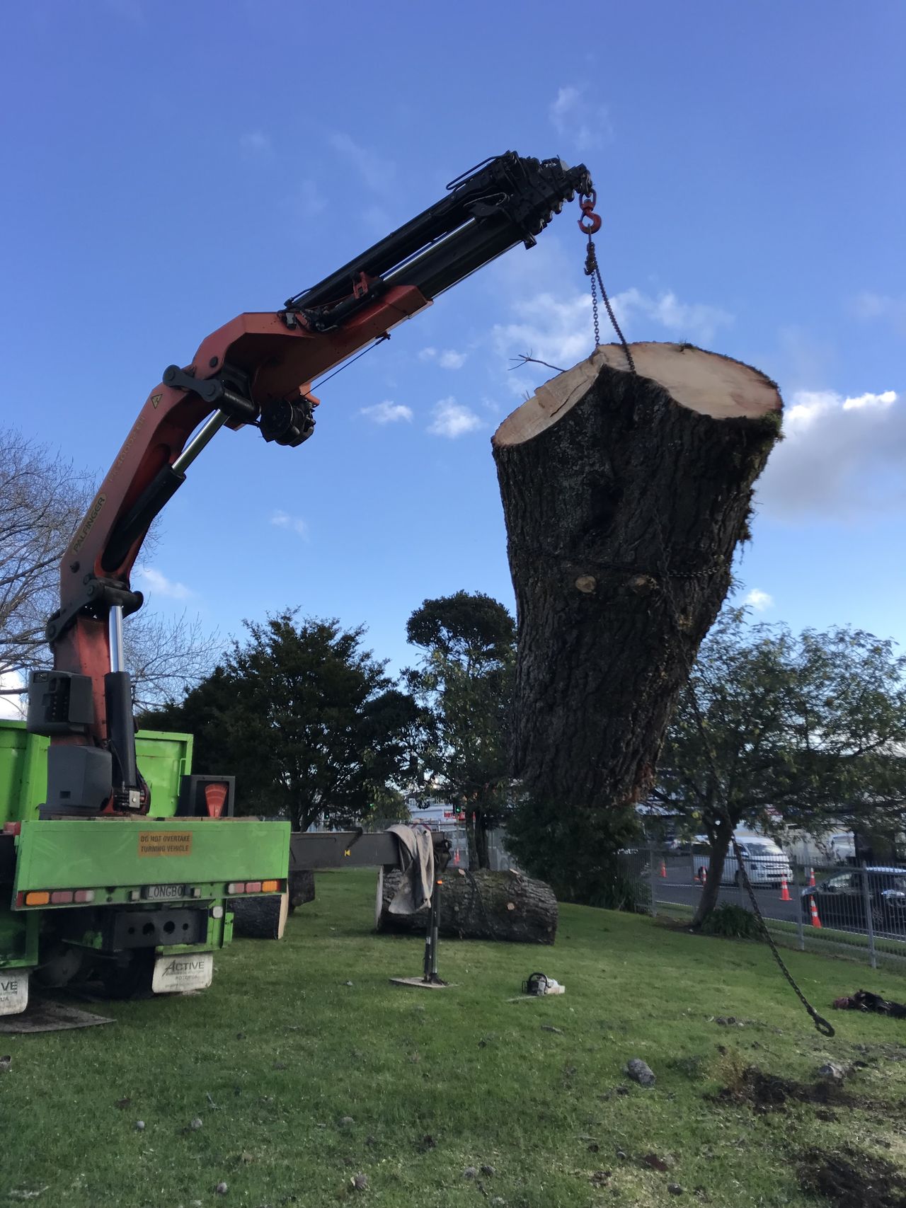 A large tree trunk section suspended from the crane above the truck deck