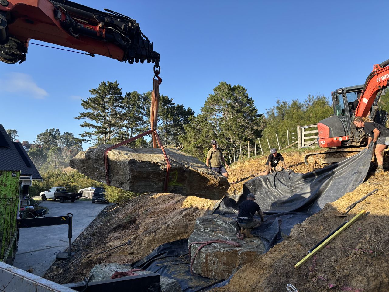 Placing large rock into a landscaped bank.
