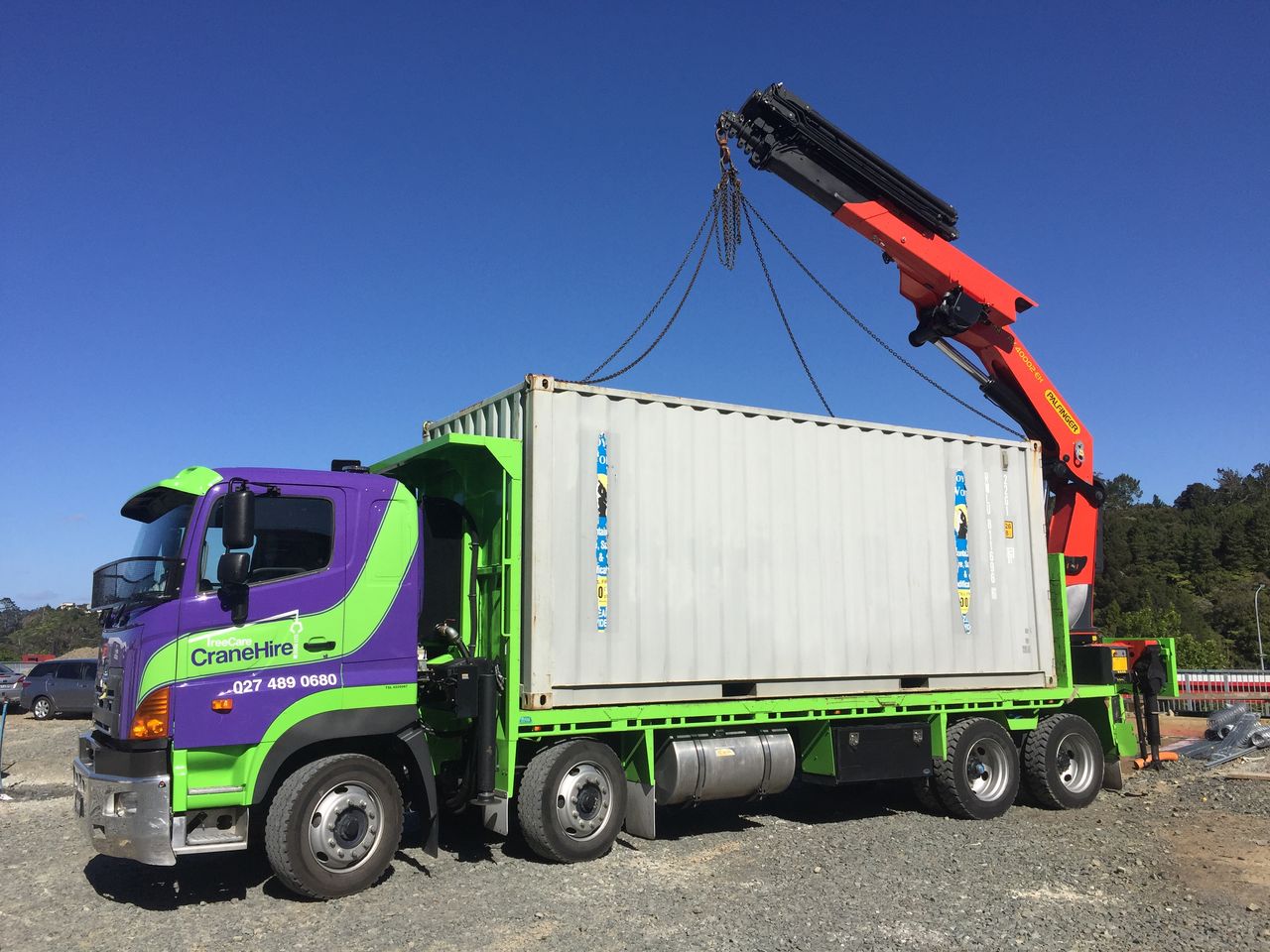 A 20-foot shipping container being lifted from the truck deck