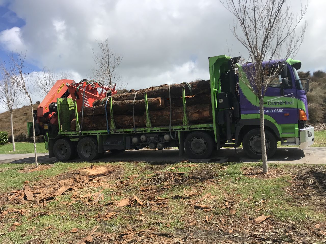 The truck loaded with strapped log sections, the crane folded at the rear